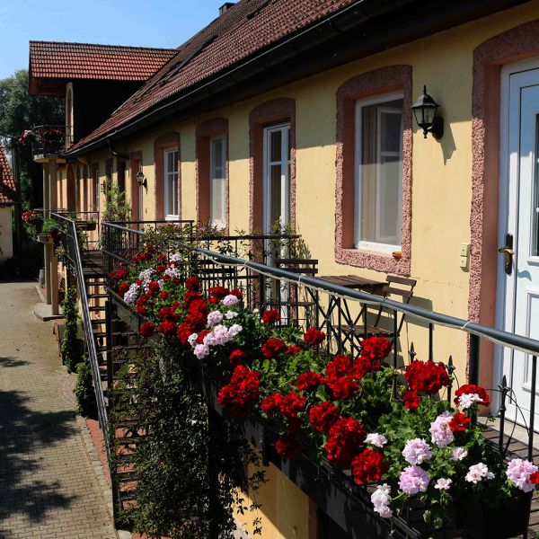 Ferienwohnungen am Gersthof mit Geranien am Balkongeländer und Eingangstür zum Hof