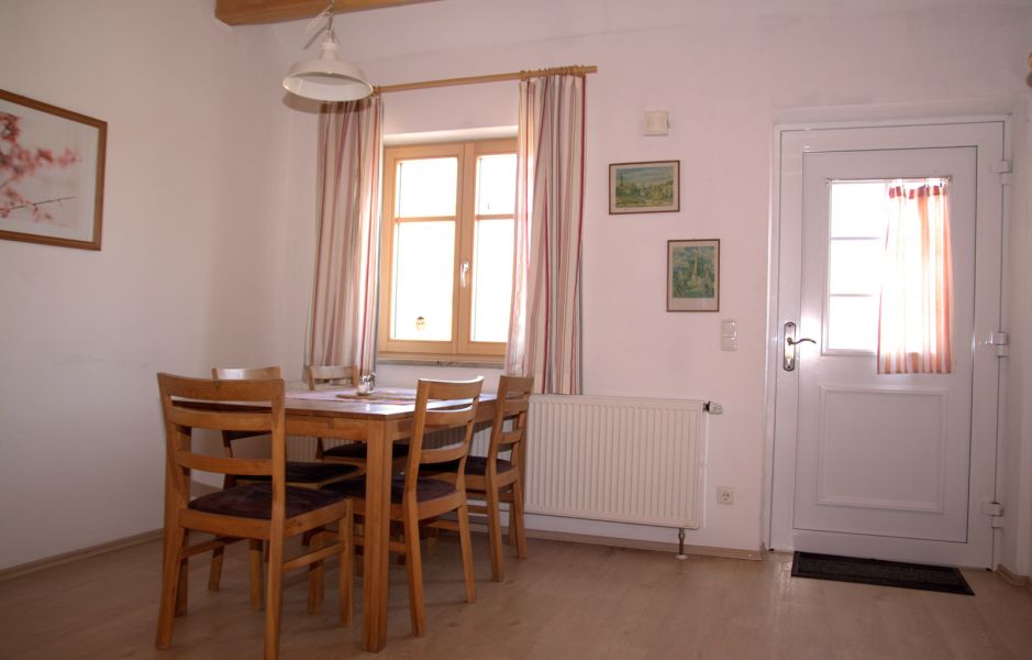Essbereich einer Ferienwohnung am Gersthof mit Holztisch, Stühlen und Fenster zum Hof