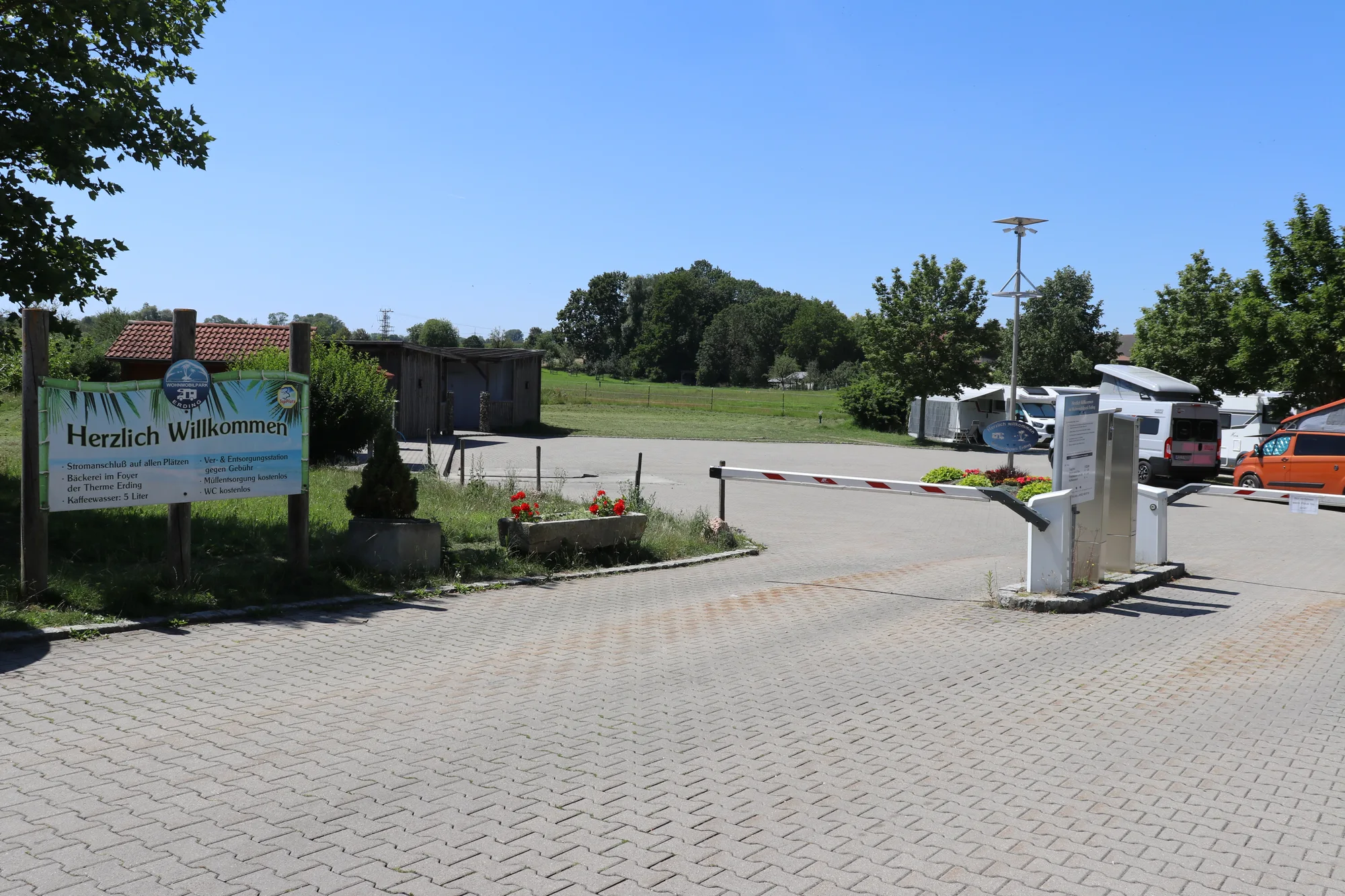 Einfahrt zum Wohnmobilpark Erding mit Schranke, Ticketsäule und Willkommensschild