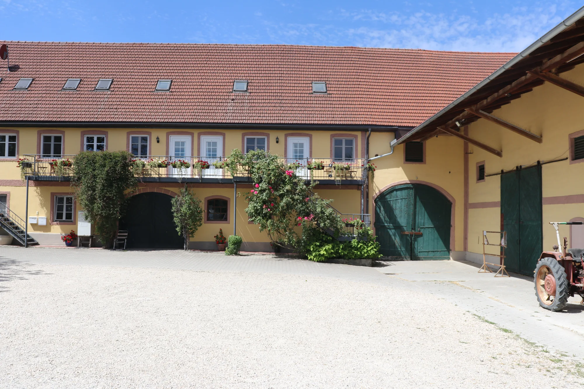 Gersthof mit historischem Hofgebäude und altem Traktor auf dem Kiesplatz