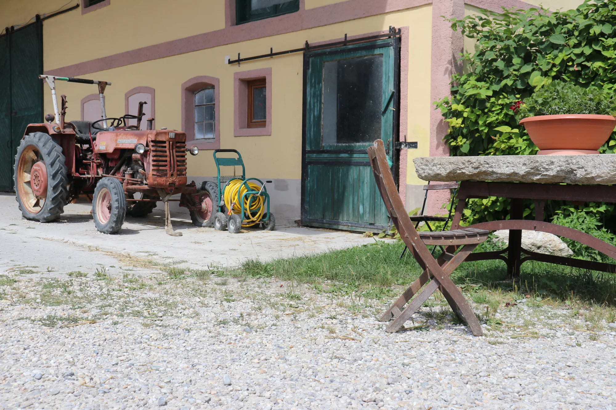 Roter Oldtimer-Traktor vor dem Wirtschaftsgebäude des Gersthofs