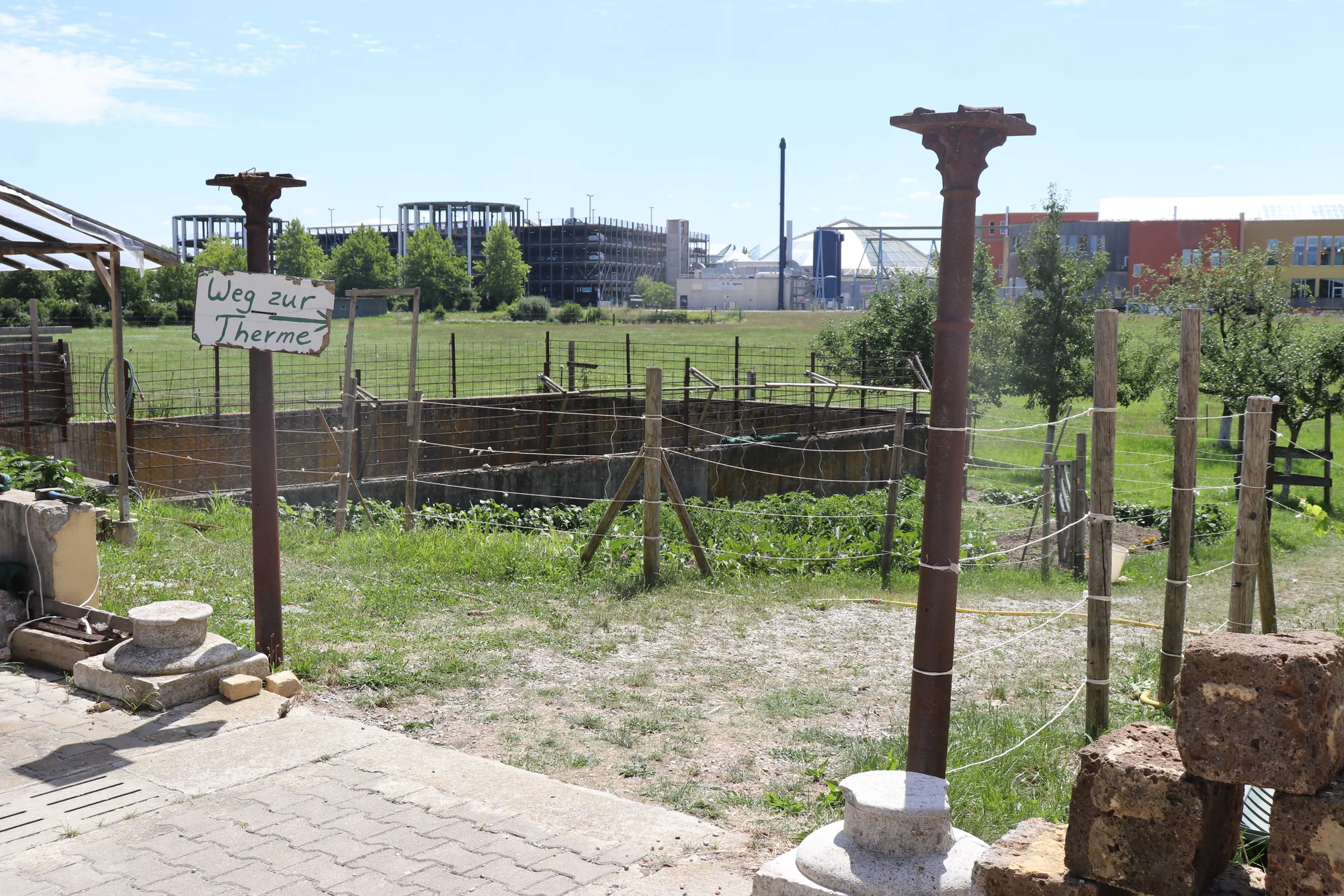 Schild Weg zur Therme am Zaun, dahinter die Gebäude der Therme Erding