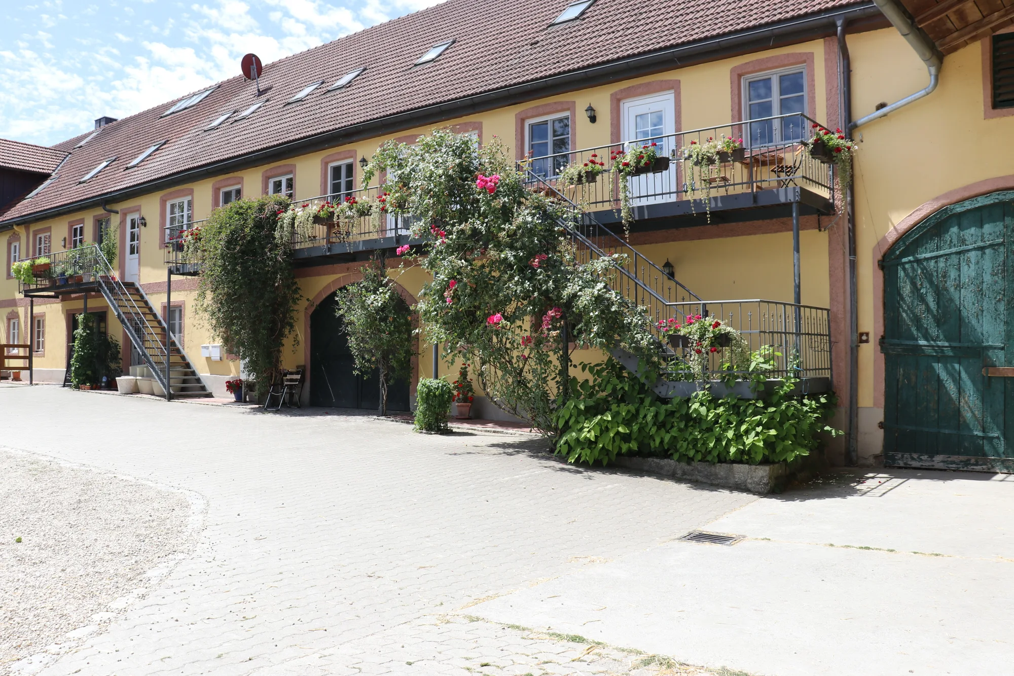 Hofgebäude des Gersthofs mit Balkonen, Rosen und Außentreppen