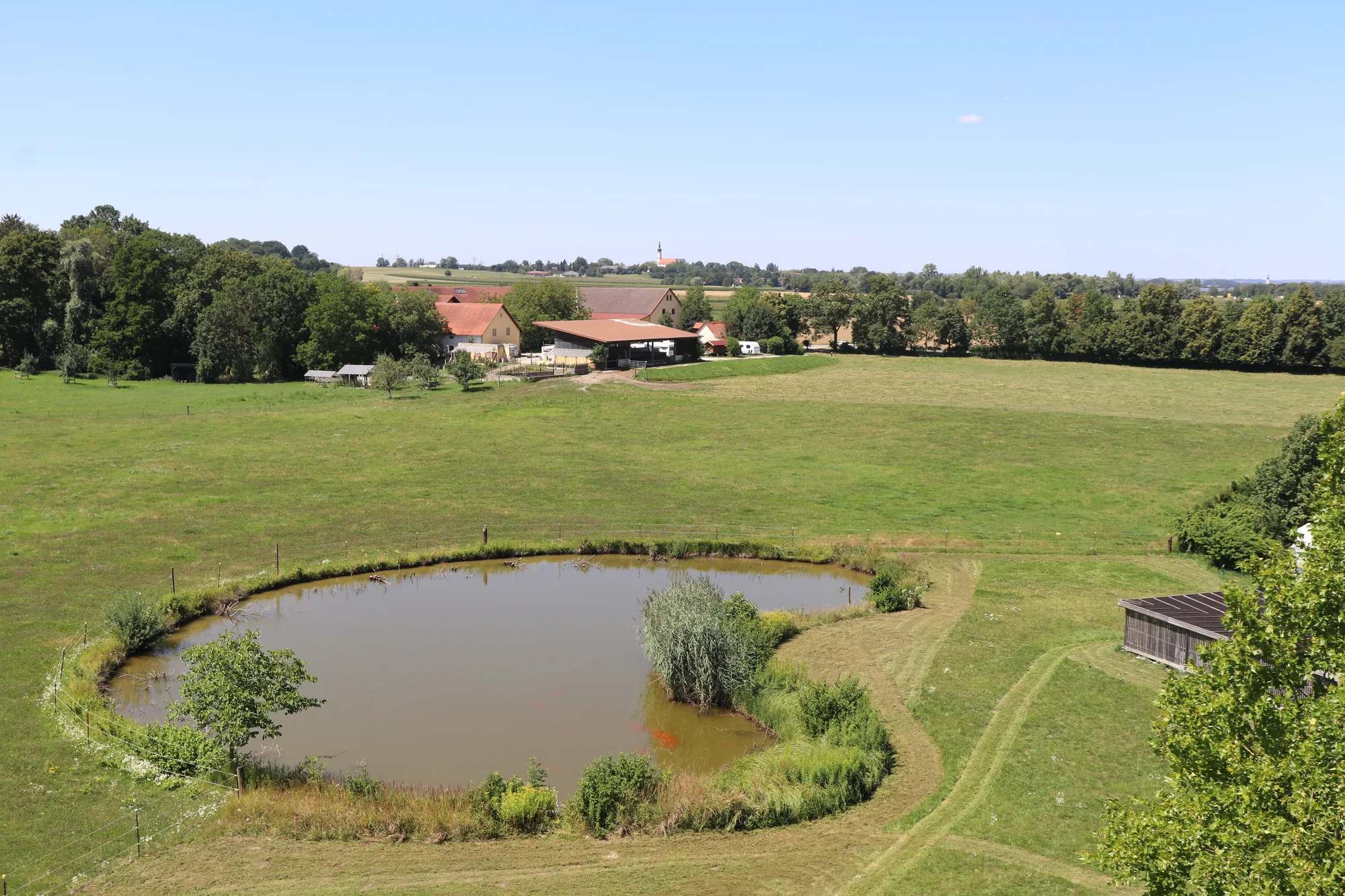 Weiher auf der Wiese hinter dem Gersthof mit Hofgebäuden im Hintergrund