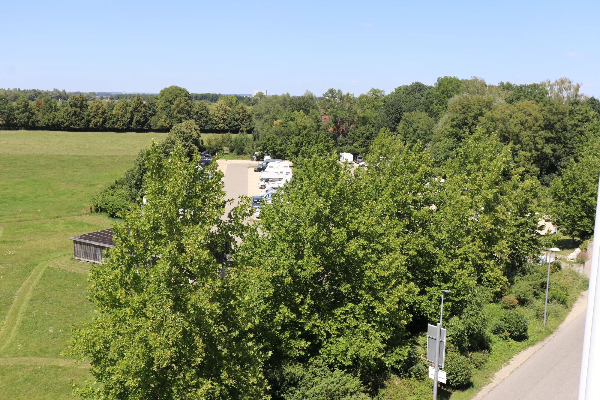 Blick über Baumkronen auf den Wohnmobilpark Erding und die angrenzenden Felder