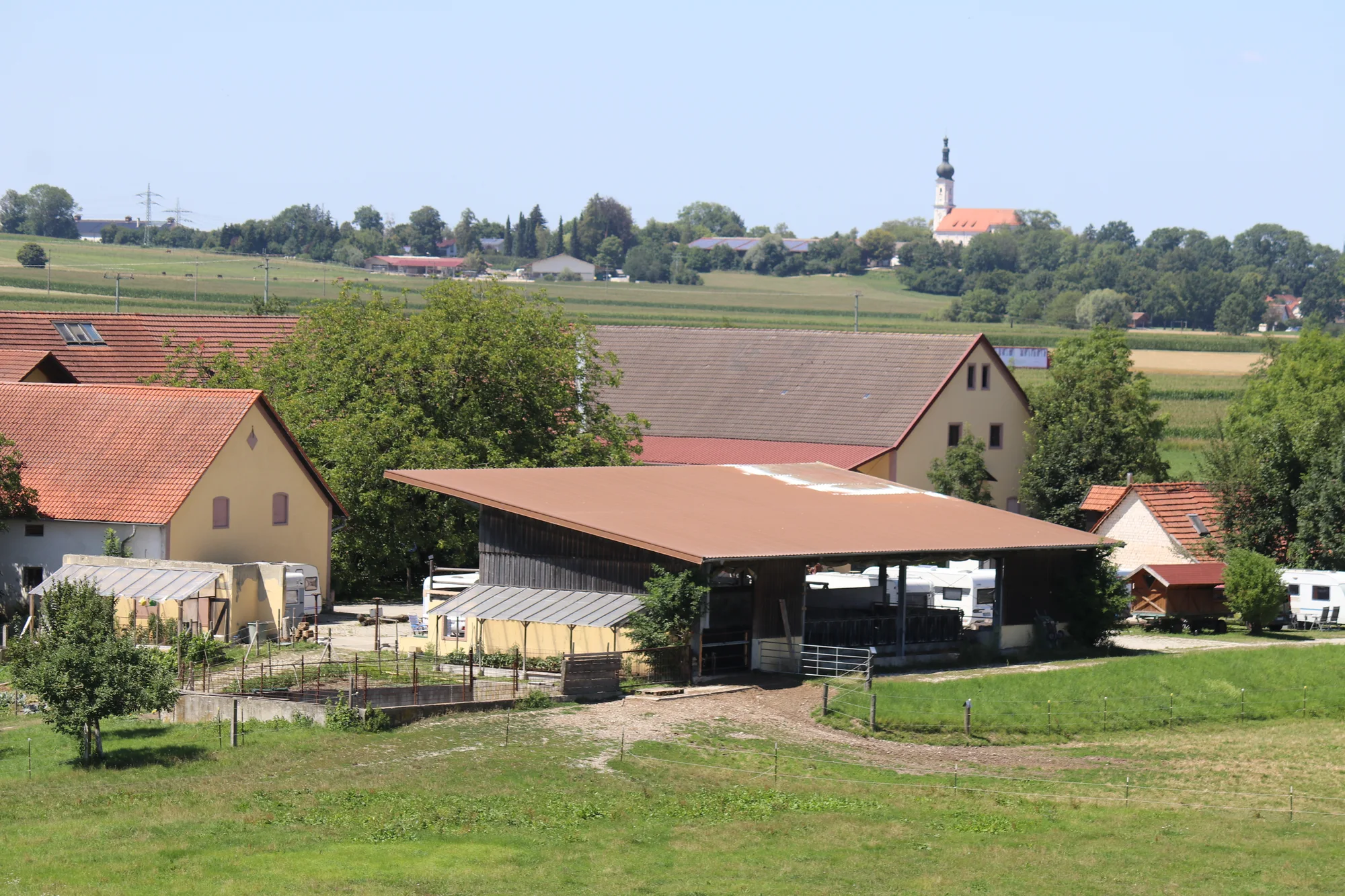 Offenstall und Hofgebäude des Biohofs Gersthof vor der oberbayerischen Landschaft