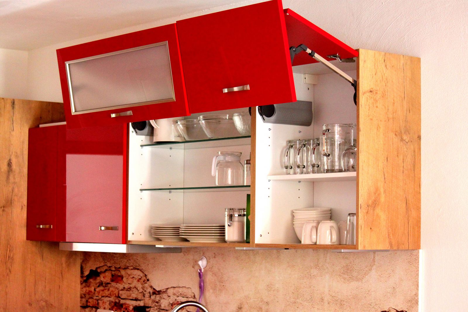 Küche einer Ferienwohnung am Gersthof mit rotem Oberschrank, Gläsern und Geschirr