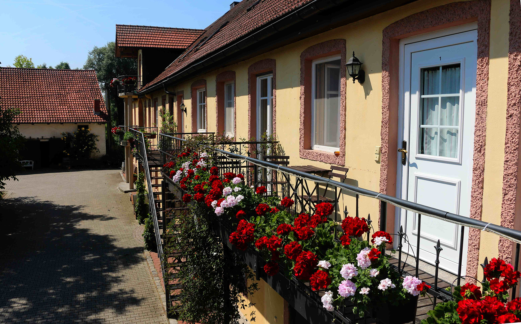 Ferienwohnungen am Gersthof mit Geranien am Balkongeländer und Eingangstür zum Hof