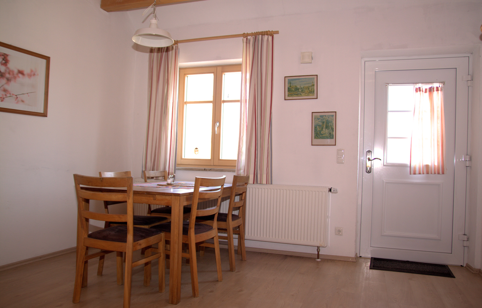 Essbereich einer Ferienwohnung am Gersthof mit Holztisch, Stühlen und Fenster zum Hof